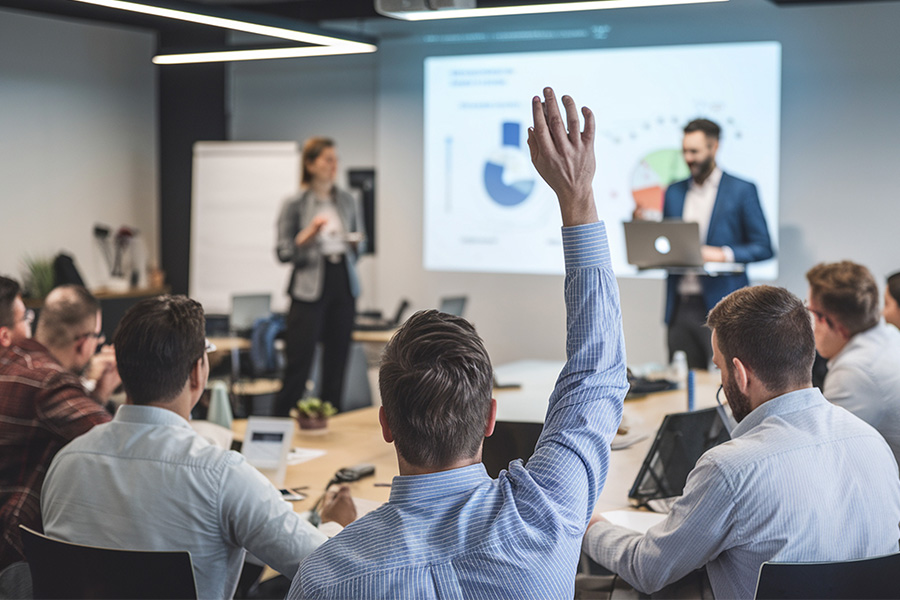 mixed group of business professionals attending a conference. one person has their hand raised